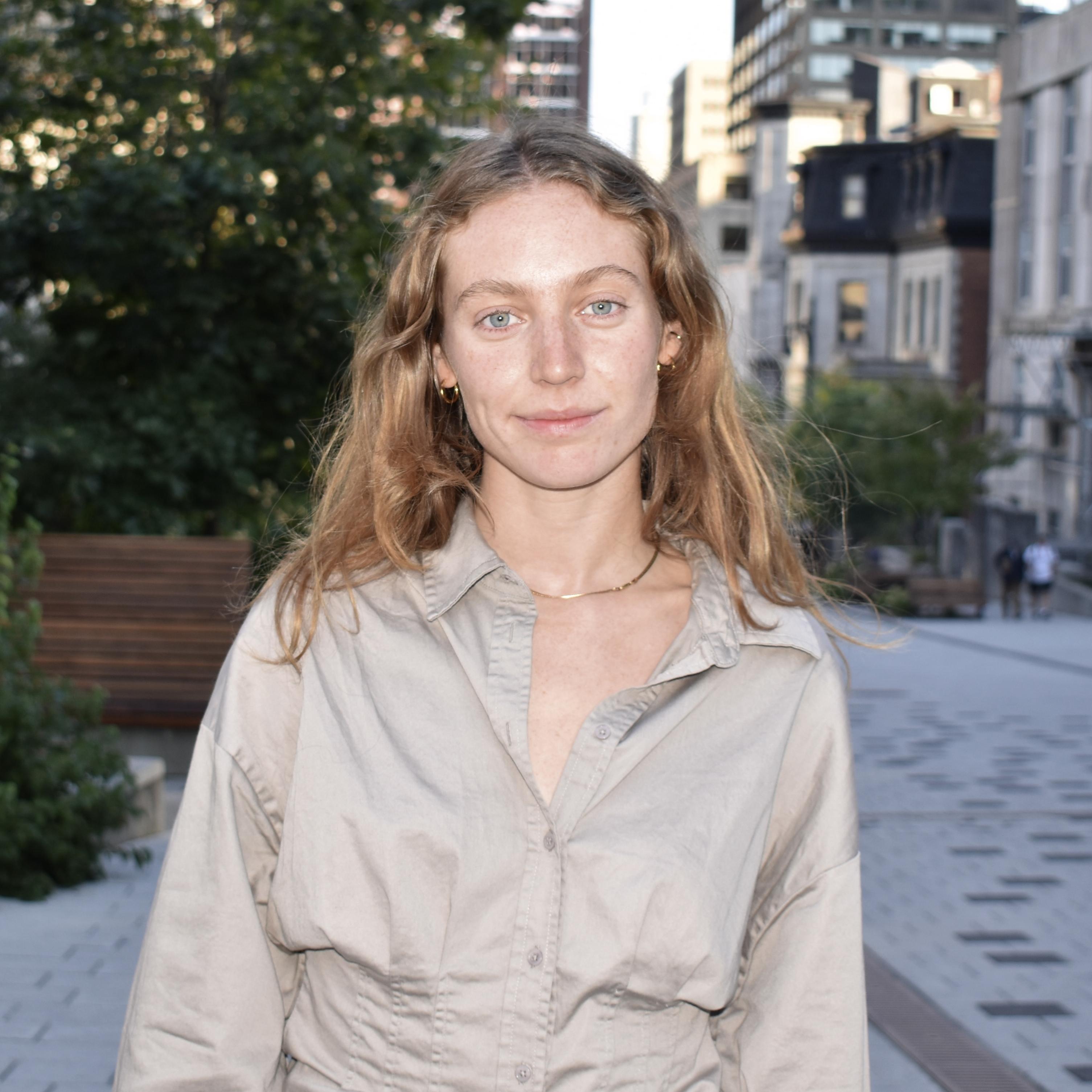 Ophélie Bourque, souriante, se tient devant l'école de gestion de McGill, portant une tenue professionnelle. 